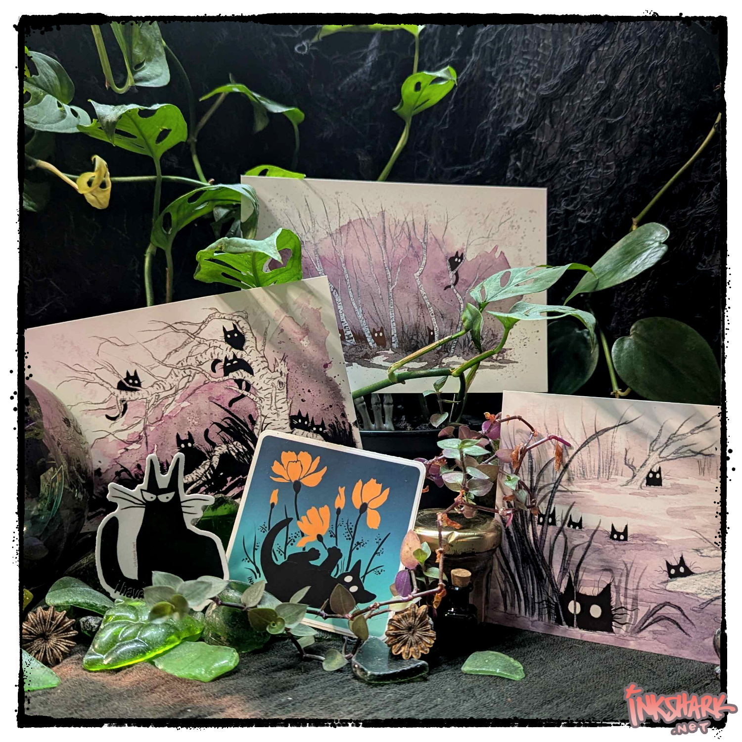 all the postcards and stickers that feature black cats arranged on a mound of worn seaglass and crowned in vines