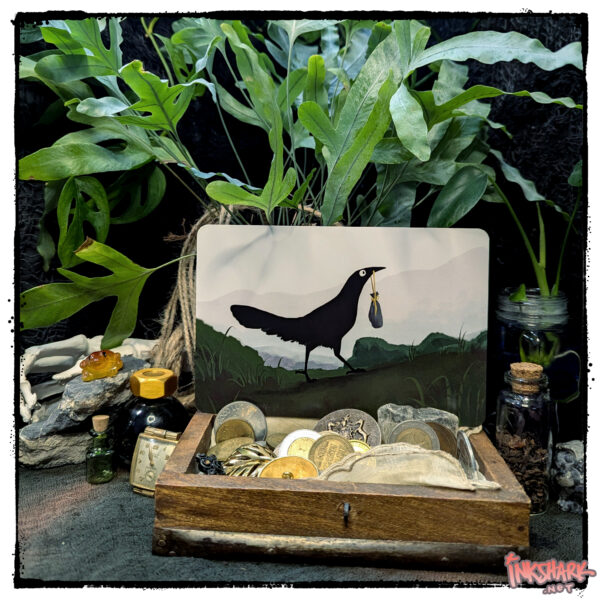 Postcard of a crow with a pouch in its beak striding up a mountain; product is posed in a wooden treasure chest filled with old coins and jewelry