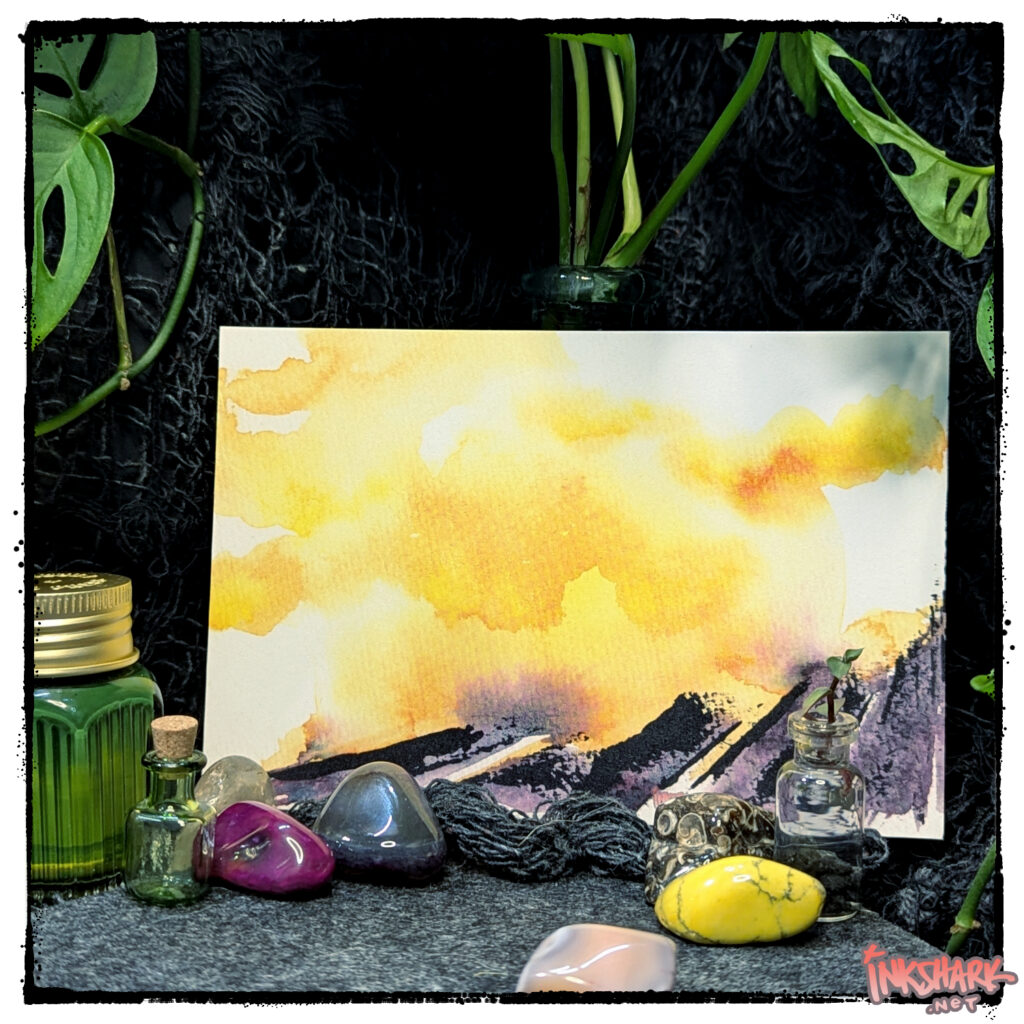 Postcard featuring an abstract watercolor of a volcano, posed with a handful of polished rocks and some live plants