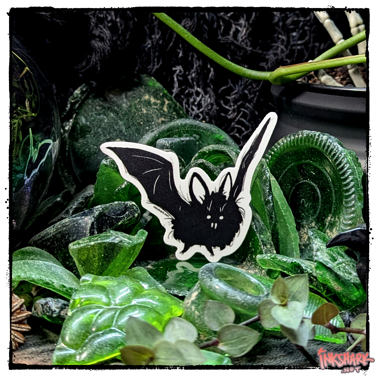 Sticker of a bat perched in a mass of adventurous green sea glass, with live plants guarding it