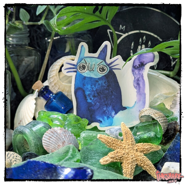 Sticker of a smug abstract cat; product is perched on a mountain of seaglass, and shells and nestled in foliage