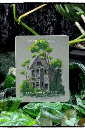 Sticker of a grey abandoned house bursting with healthy foliage, posed on a small hill of worn sea glass that's framed with live foliage