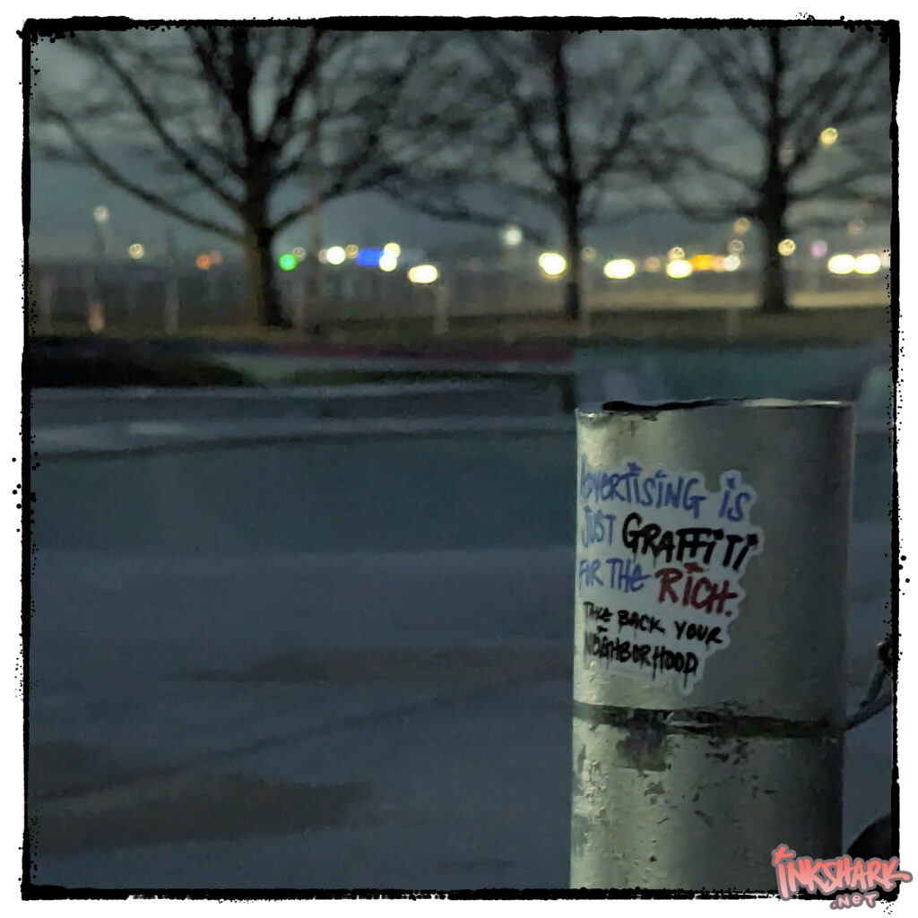 Photo of a sticker on a pole at a skatepark. My handwriting: "Advertising is just graffiti for the rich. Take back your neighborhood." Writing is stylized and drippy like a paint marker